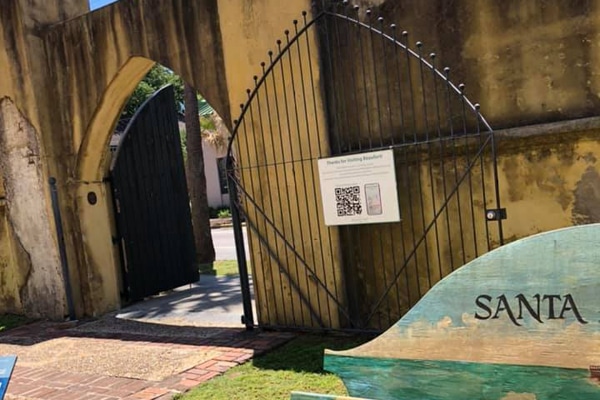 Wrought iron gate open in a stone wall, with signs and "SANTA"—perfect for a Fripp Island family vacation.