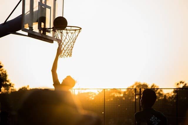 Silhouette of a person shooting a basketball into a hoop at sunset during a South Carolina vacation.