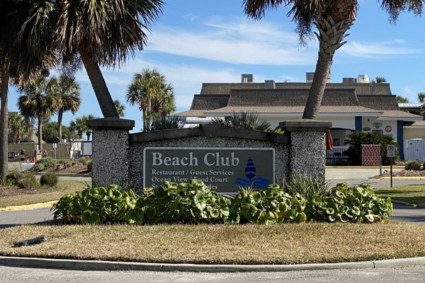 Beach Club sign with palm trees and a building in the background on a sunny Fripp Island vacation rental day.