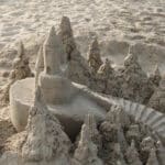 A detailed sandcastle with towers, trees, and a winding staircase on a South Carolina vacation beach.