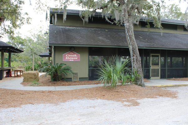A rustic building with a sign reading The Creek House, surrounded by trees, perfect for a Fripp Island vacation rental.