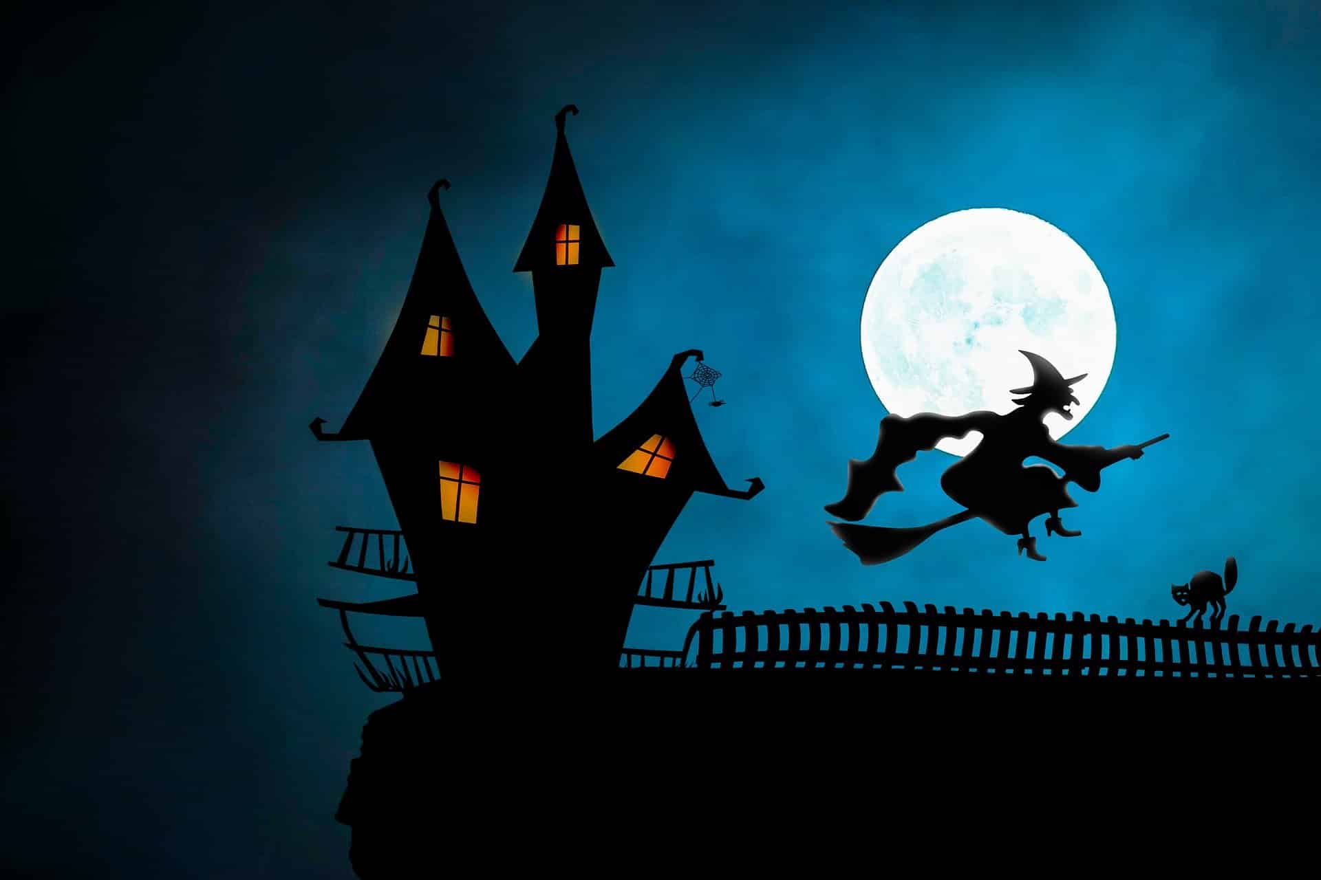 Silhouette of a witch on a broom flying past a spooky house and full moon over Fripp Island's lowcountry.
