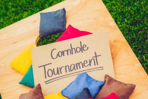 A sign reading Cornhole Tournament on a wooden board, surrounded by colorful bean bags, highlights a Fripp Island family vacation.