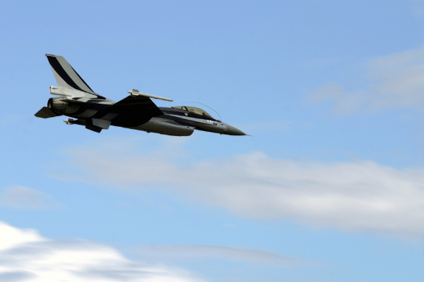 A fighter jet soars over the Lowcountry sky with clouds drifting below.