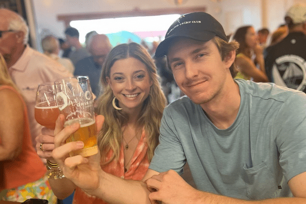 Smiling woman and man holding beers, enjoying a lively indoor gathering with a hint of Lowcountry charm.