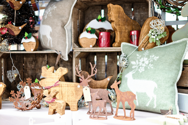 Wooden and metal deer decorations, festive ornaments, and a green cushion evoke a cozy Lowcountry holiday display.