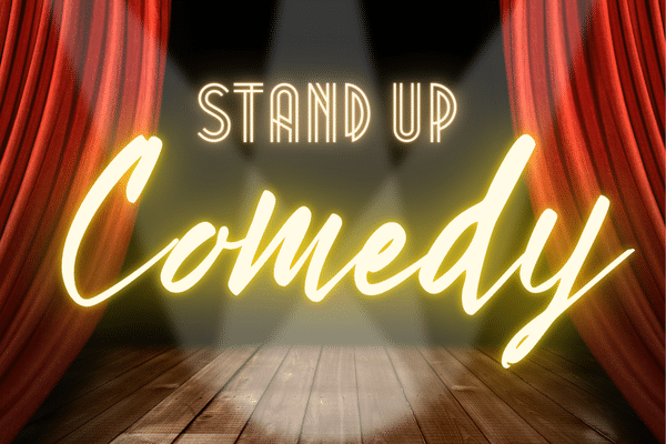 A stage with red curtains and spotlights, displaying the words Stand Up Comedy in glowing text.