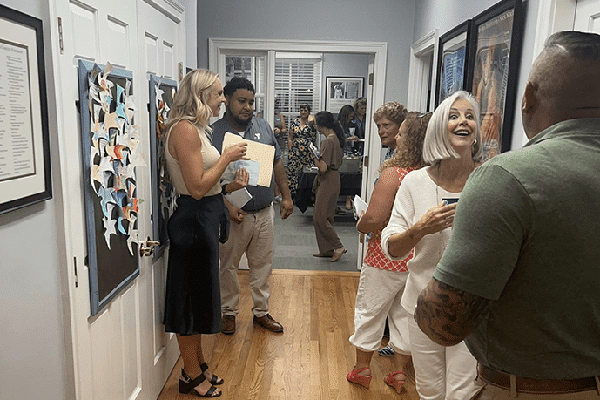 People chatting and socializing in a hallway during a casual lowcountry indoor event or gathering.