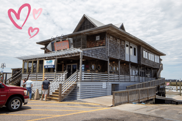 Wooden seafood restaurant on Fripp Island with people outside, red truck parked, and pink heart doodles in the sky.