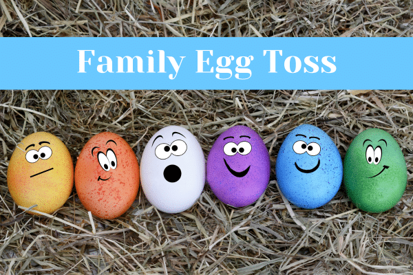 Six colorful eggs with faces on hay, under a blue banner that reads Family Egg Toss—perfect for your beach vacation.