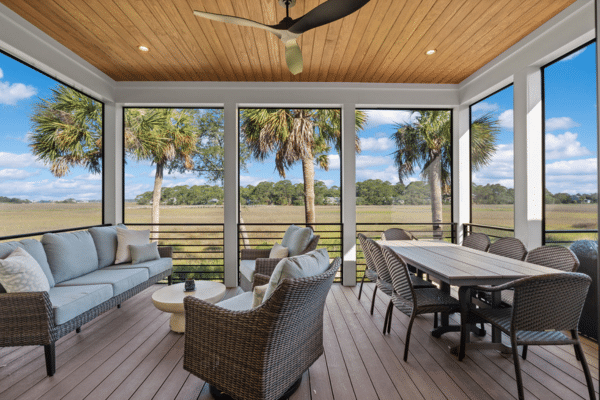 Screened porch with wicker furniture, dining table, ceiling fan, wood ceiling, and a scenic outdoor view.