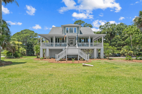 Gray raised Fripp Island home with large porch, American flag, and lush lawn—perfect for your next Fripp beach vacation.