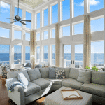 Bright living room with large windows, ocean view, a sectional sofa, and light streaming in.