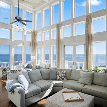 Bright living room with large windows, ocean view, a sectional sofa, and light streaming in.