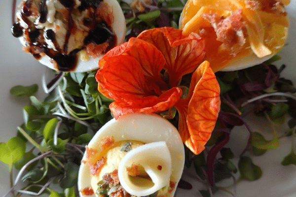 Three deviled eggs garnished with vibrant microgreens and an orange edible flower on your South Carolina vacation.