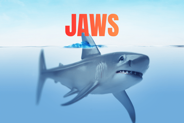 A shark swims near the surface at a Fripp Island Swim In Movie, with JAWS in bold red letters above the water.
