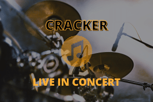 Drum set and microphones with text: CRACKER LIVE IN CONCERT overlaid in bold yellow letters.