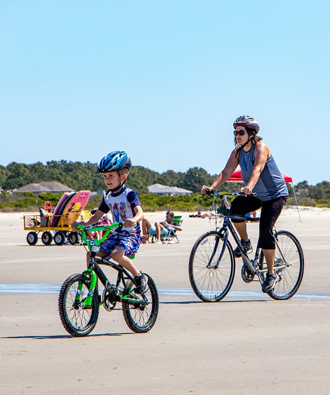 Mother and son riding bikes on beach