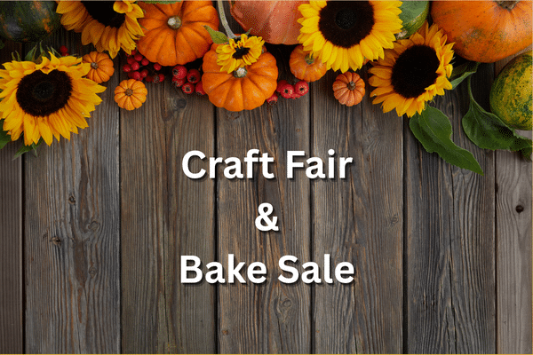 Sunflowers, pumpkins, and leaves border a Craft Fair Bake Sale sign on a wooden background.